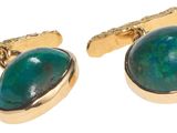 un gros plan sur une paire de boutons de manchette verts sur fond blanc