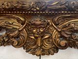 a gold frame with a face on it in front of a mirror