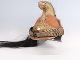 un casque surmonté d'un cheval, posé sur un socle