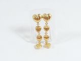 une paire de boucles d'oreilles en or en forme de cœur, présentées dans une boîte transparente posée sur un fond blanc