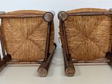 two wooden chairs with wicker seats are sitting on a white surface