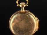 an antique gold pocket watch with a chain on a black surface