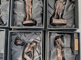 six bronze statues of women in boxes on a white surface