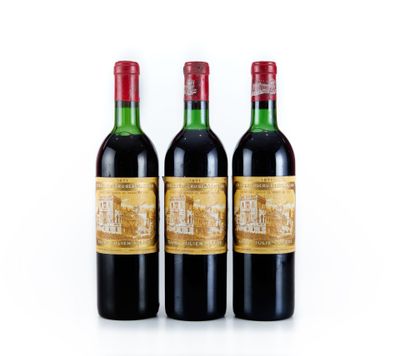 trois bouteilles de vin rouge posées l'une à côté de l'autre sur une surface blanche