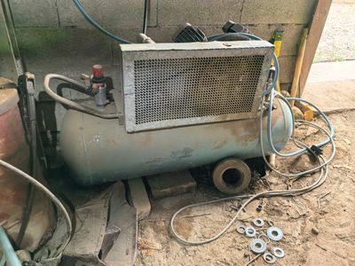an old air conditioner sitting on the ground next to a pile of tools
