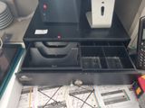 a coffee maker sitting on top of a desk next to a cell phone