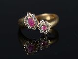 a close up of a gold ring with pink stones on a black surface