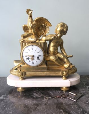 une horloge en or sur laquelle sont représentés un garçon et un coq