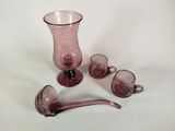 des vases et des tasses en verre violet posés sur une surface blanche, avec une cuillère