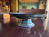 a silver plate on a wooden table with a birdcage in the background