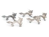 trois figurines de dragons en argent sur fond blanc