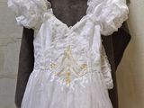 a white dress hanging on a hanger next to a brick wall