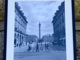 photographie en noir et blanc représentant des personnes traversant une rue, avec une tour horloge en arrière-plan