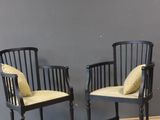 two black chairs with yellow cushions against a gray wall