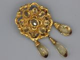 an image of a gold broochle with two tears and two tears