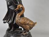 bronze statue of a man and a goose on a marble base