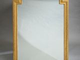 un miroir à cadre doré posé sur une surface blanche, avec un fond blanc