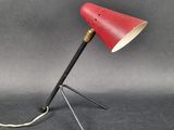 une image représentant une lampe rouge posée sur un trépied
