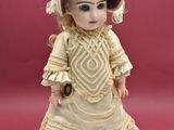 a doll that is wearing a dress and a hat
