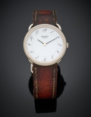 une montre à cadran blanc avec un bracelet en cuir marron, posée sur un fond noir