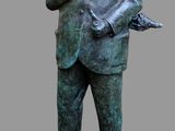 statue d'un homme portant un chapeau et une canne, debout sur un socle