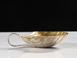 a silver and gold bowl on a white table with a black background