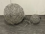 two balls of wire sitting on the floor next to each other