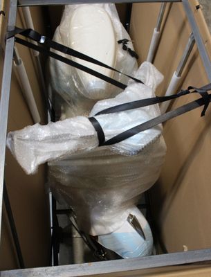 des toilettes emballées dans du plastique et placées à l'intérieur d'un carton
