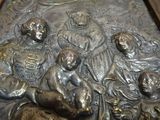 a metal relief of a group of people on a bench