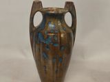 a brown vase with blue spots on it on a white background