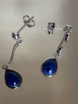 une paire de boucles d'oreilles en pierre bleue avec des crochets en argent, posée sur une table