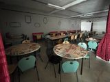 many tables and chairs in a room with a red curtain