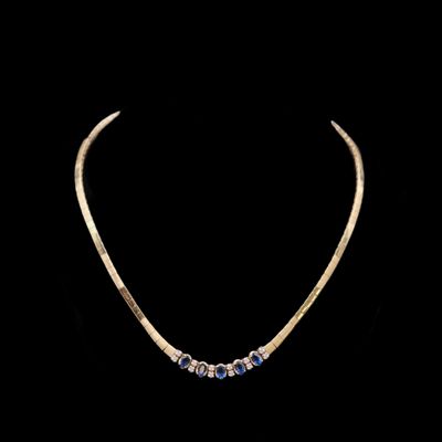 un collier en or orné de pierres bleues sur fond noir