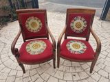 two red chairs with floral designs on them sitting on a brick patio