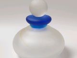 a small glass bottle with a blue top on a white surface