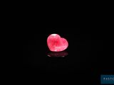 un gros plan sur une pierre rose en forme de cœur posée sur une surface noire