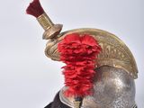 a silver helmet with a red feather on top of it