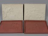 une paire de boîtes rouges et blanches ornées de sculptures, posées sur une surface grise