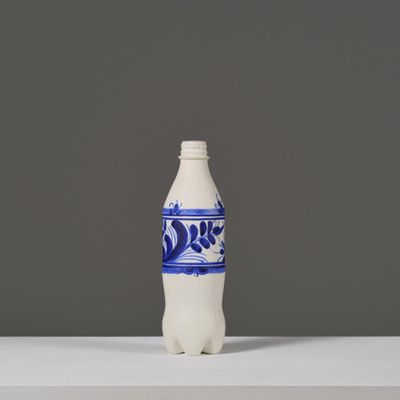 une bouteille bleue et blanche posée sur une table, sur fond gris