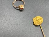 two gold rings and a stick on a table