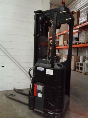 a forklift in a warehouse with shelves and pallets in the background