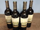four bottles of wine are lined up on a wooden table