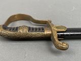 a gold colored sword with a black handle on a table