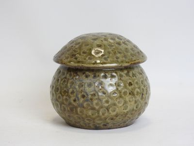a small green pot with a lid on a white surface