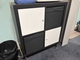 a black and white chest of drawers next to a trash can