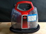 un aspirateur rouge et noir posé sur une table en bois