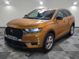 La voiture orange est garée sur un sol à damier dans le garage.