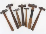 six old hammers are lined up in a row on a white surface