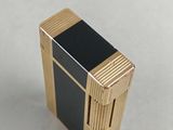a black and gold lighter sitting on a white surface