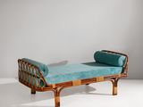 un lit de repos en rotin rembourré, sur lequel repose un coussin bleu